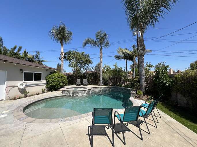Vacation Rental With Pool, Palm Trees, And Patio Chairs