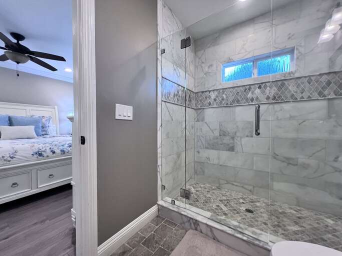 Glass Shower Stall And Grey Flooring In A Well-lit Bathroom