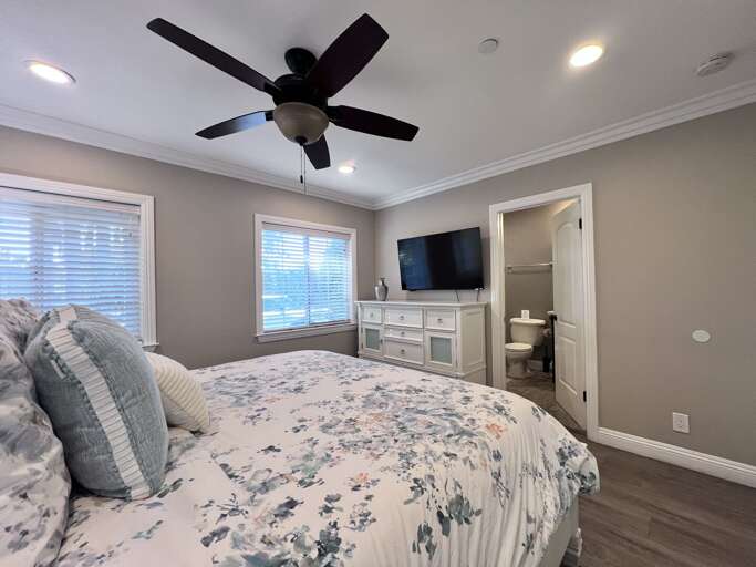 Bedroom With Floral Bedding, Black Ceiling Fan, And Built-in Shelves