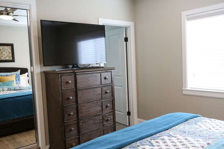 Bedroom With Blue Bedspread, Brown Dresser, And Mounted Television Bedroom With Blue Bedspread, Brown Dresser, And Mounted Television