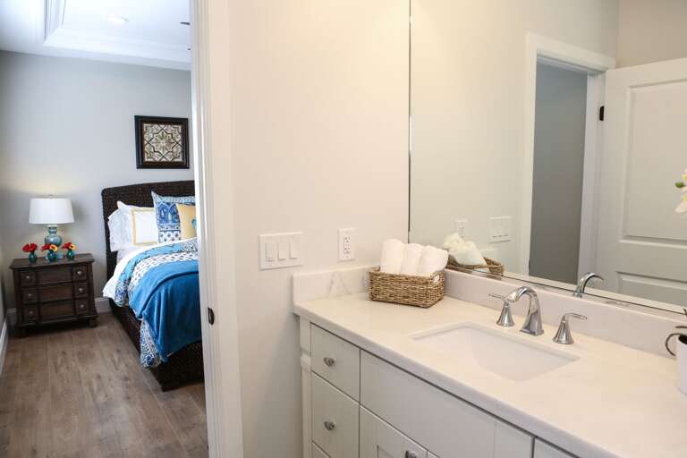 View From Bathroom Showing Sink Leading To Bedroom With Blue Bedding View From Bathroom Showing Sink Leading To Bedroom With Blue Bedding