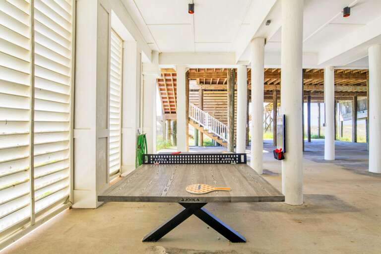 Outdoor pingpong table under the house on ground level.