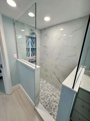 Refresh in this sleek, marble-accented walk-in shower featuring rainfall showerhead, built-in shelving, and stylish tile flooring. Refresh in this sleek, marble-accented walk-in shower featuring rainfall showerhead, built-in shelving, and stylish tile flooring.