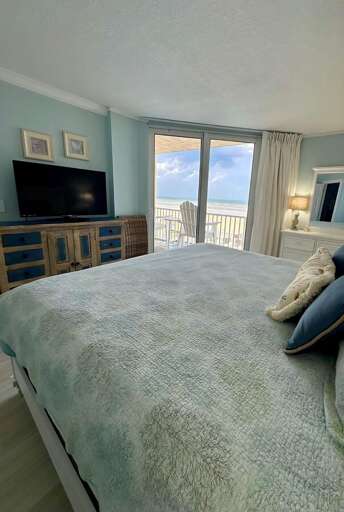 Wake up to stunning beach views from this cozy, light-filled bedroom featuring coastal decor, a private balcony, and flat-screen TV. Wake up to stunning beach views from this cozy, light-filled bedroom featuring coastal decor, a private balcony, and flat-screen TV.