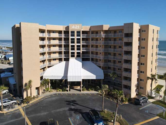 Experience coastal beauty from above! Enjoy an aerial view of the oceanfront building, surrounded by breathtaking scenery.