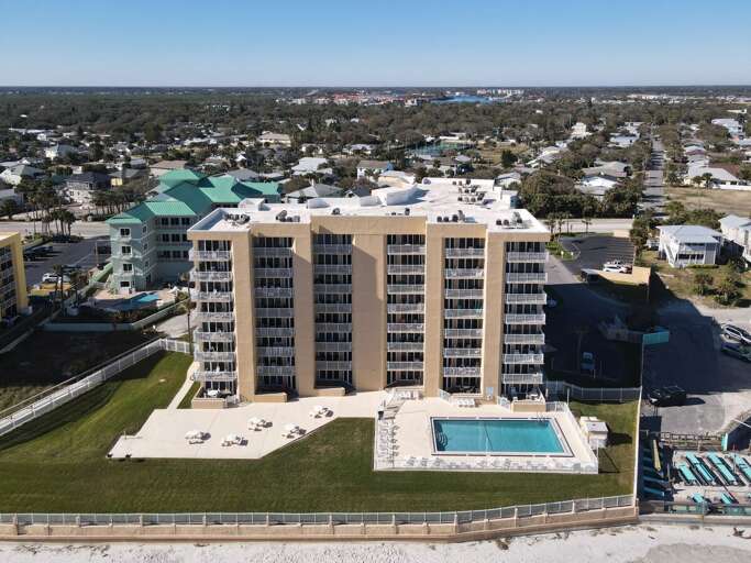 Experience coastal beauty from above! Enjoy an aerial view of the oceanfront building, surrounded by breathtaking scenery.