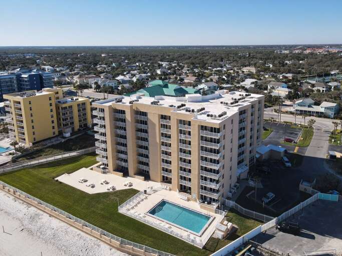 Experience coastal beauty from above! Enjoy an aerial view of the oceanfront building, surrounded by breathtaking scenery.