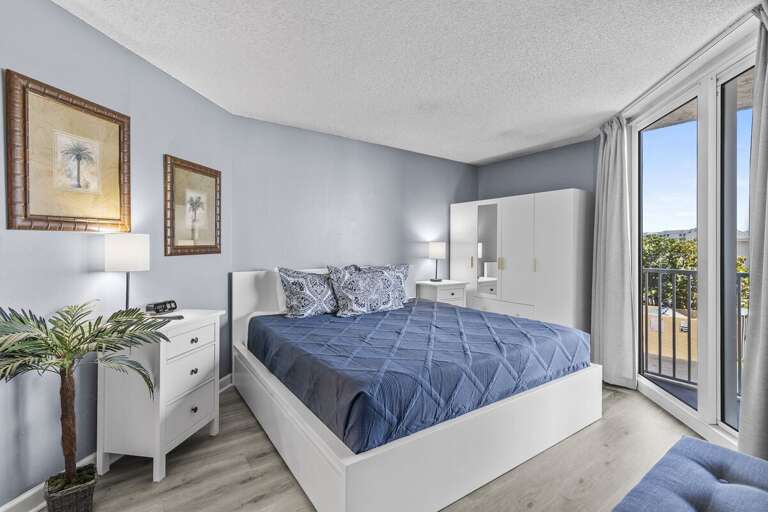 Retreat to comfort! The master bedroom features a queen bed and a view to the balcony for serene relaxation.