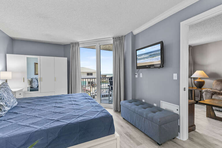Retreat to comfort! The master bedroom features a queen bed and a view to the balcony for serene relaxation.