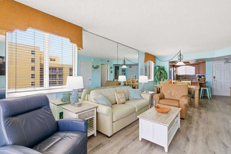 Inviting open-concept living area with cozy seating, coastal decor, and adjoining kitchen and dining