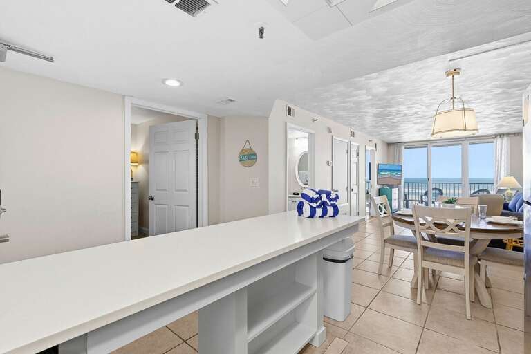 This inviting beach stay features a spacious kitchen island, open dining area, and glimpses of ocean views. Perfect for gathering, dining, and relaxing after a fun-filled day at the beach.