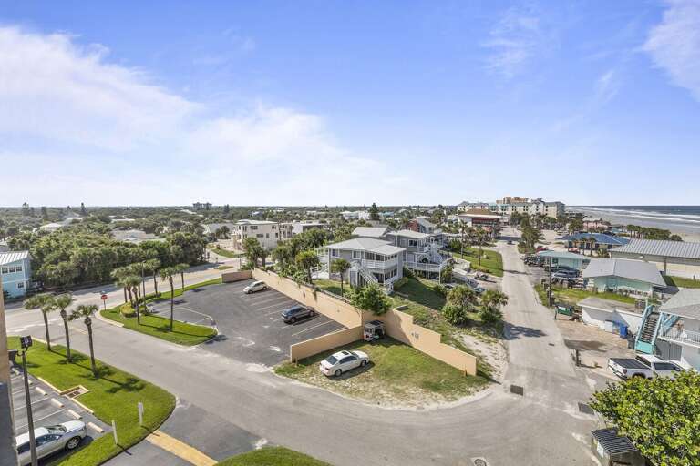 This captivating aerial shot captures a peaceful coastal neighborhood, with charming homes and lush greenery. The view extends toward the ocean, offering a glimpse of the nearby beach. This captivating aerial shot captures a peaceful coastal neighborhood, with charming homes and lush greenery. The view extends toward the ocean, offering a glimpse of the nearby beach.
