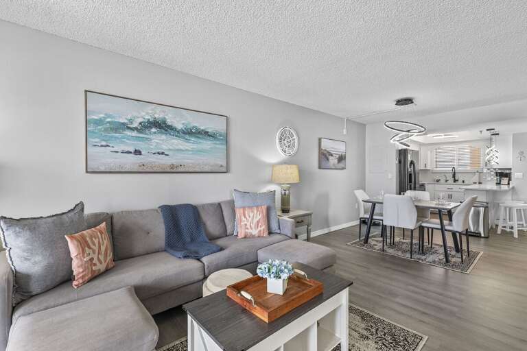 The living room is furnished with a comfortable sectional sofa adorned with coral-patterned pillows and soft throws, creating a cozy space for relaxation. The living room is furnished with a comfortable sectional sofa adorned with coral-patterned pillows and soft throws, creating a cozy space for relaxation.