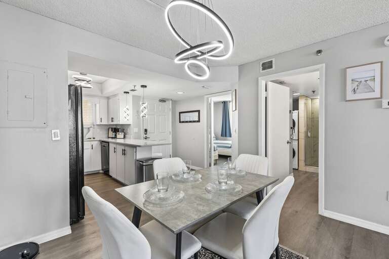 This modern dining area is illuminated by a striking circular light fixture, adding a touch of This modern dining area is illuminated by a striking circular light fixture, adding a touch of