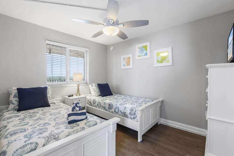 Vacation Rental Room With Twin Beds, Serene Sea-themed Linens And Light Laminate Flooring