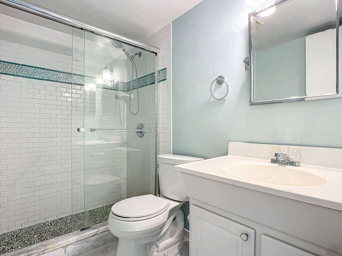 Enjoy the clean, updated bathroom with a walk-in glass shower and contemporary finishes. Enjoy the clean, updated bathroom with a walk-in glass shower and contemporary finishes.