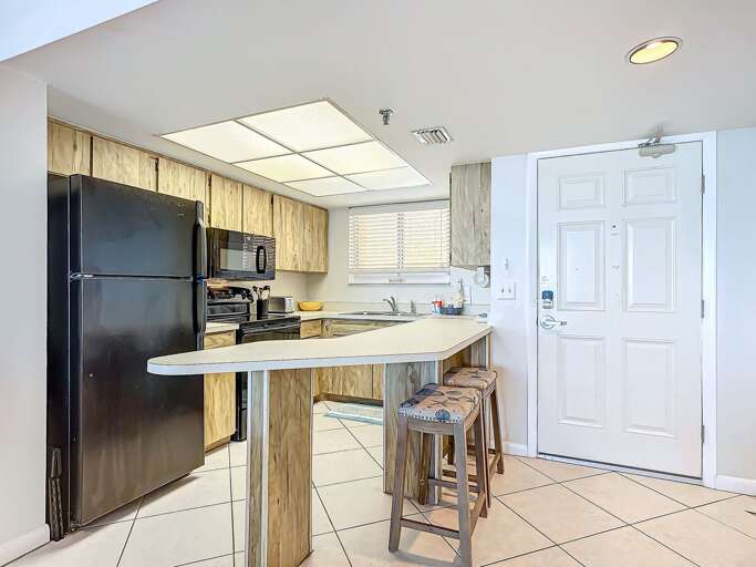 Bright, Bland Kitchen With Basic Bar Stools And Built-in Appliances