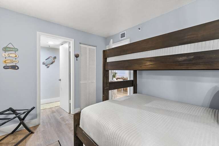 This cozy bunk room features wooden bunk beds, beach-themed wall decor, and a tranquil blue color palette, creating the perfect seaside retreat for guests or family members.