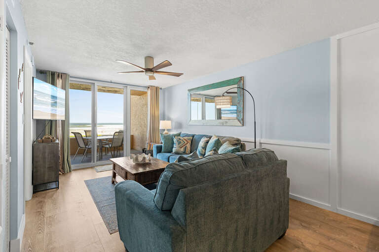 This cozy living room features plush seating, a rustic coffee table, and a wall-mounted TV. Sliding