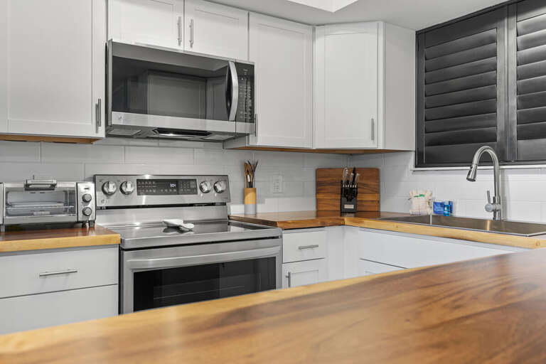 This modern kitchen features stainless steel appliances, warm wood countertops, and white cabinetry, offering a clean and functional space perfect for cooking and entertaining.