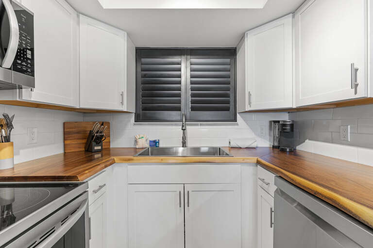 This modern kitchen showcases stainless steel appliances, white cabinetry, and warm wood countertops, creating a bright and functional cooking space. Perfect for any home chef.
