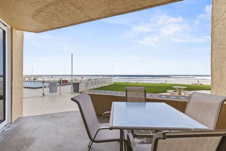 Relax on the private patio, enjoying stunning ocean views and the pool just steps away. Perfect for outdoor dining and soaking in the coastal atmosphere.