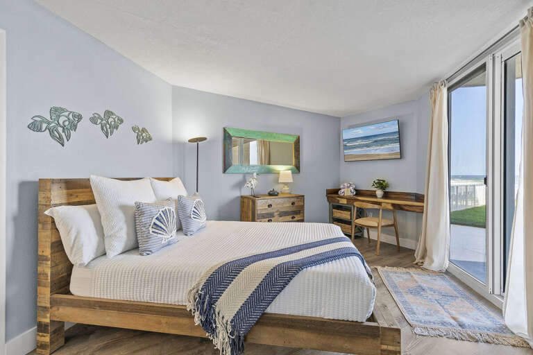 A serene bedroom featuring a rustic wood bed, coastal-themed décor, and a writing desk. Sliding
