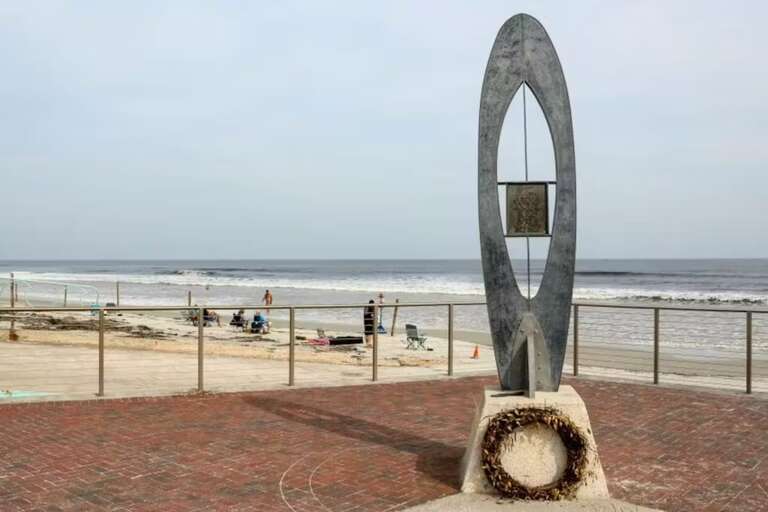 A symbolic sculpture stands on the shore, honoring the ocean's significance. Visitors can reflect on its beauty and power while enjoying the tranquil beach views in the background.