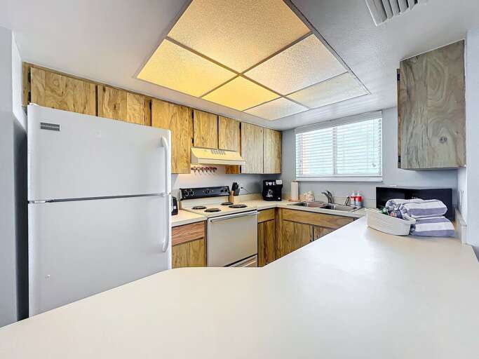 Prepare meals with ease in this well-lit kitchen featuring modern appliances, ample counter space, and a charming coastal vibe.