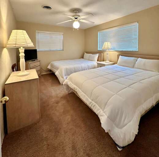 Comfortable and spacious bedroom featuring two full-size beds with cozy white bedding, soft carpet, Comfortable and spacious bedroom featuring two full-size beds with cozy white bedding, soft carpet,