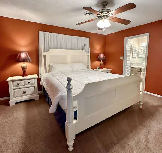Rest easy in this cozy bedroom featuring a plush king-sized bed, warm lighting, stylish matching Rest easy in this cozy bedroom featuring a plush king-sized bed, warm lighting, stylish matching