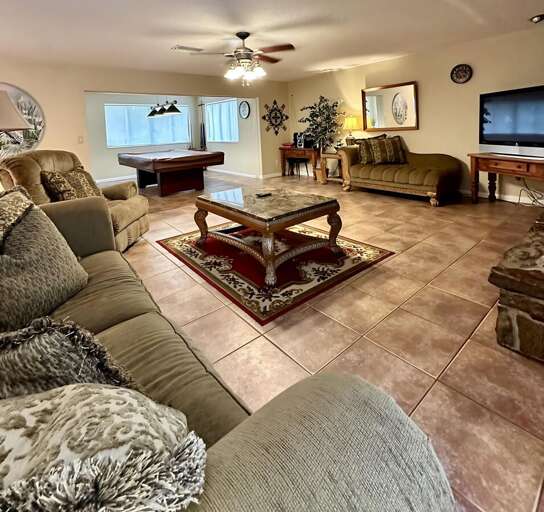 Spacious living room with plush seating, a stylish coffee table, flat-screen TV, and ceiling fan — Spacious living room with plush seating, a stylish coffee table, flat-screen TV, and ceiling fan —
