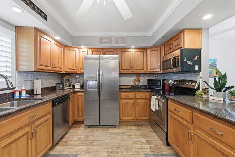 Cook with ease in this updated beach condo kitchen featuring stainless steel appliances, spacious