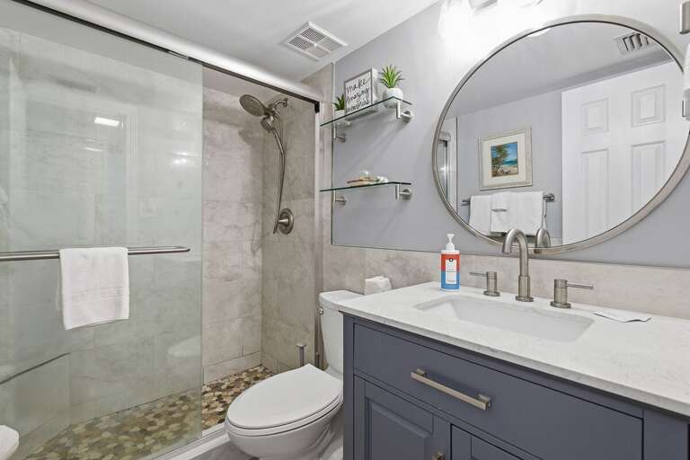 Refresh after a day at the beach in this modern coastal bathroom featuring a walk-in glass shower,