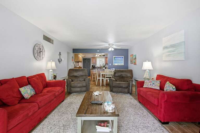 Relax in this spacious beach condo living area featuring comfortable seating, coastal décor, and an