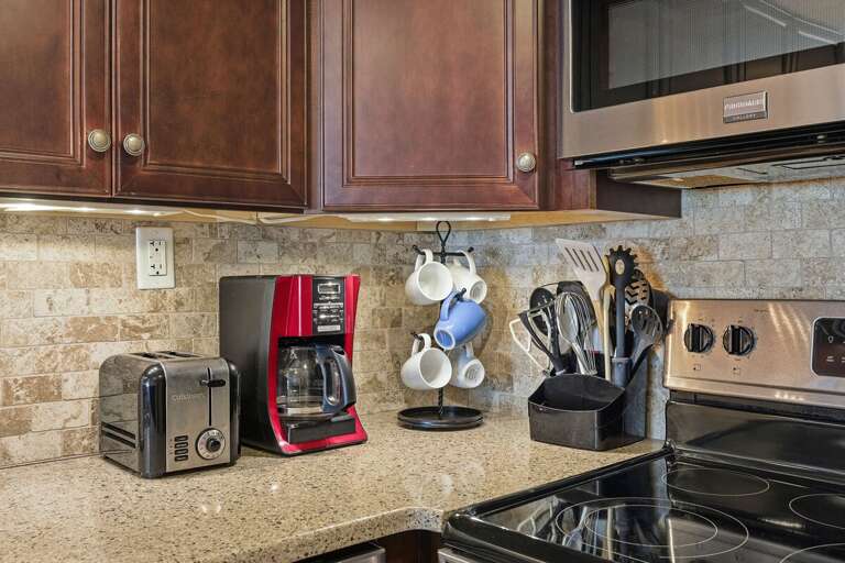 Enjoy the comforts of home in this fully equipped beach condo kitchen featuring modern appliances, cookware, and a convenient coffee station. Perfect for a relaxing and easy beach stay.