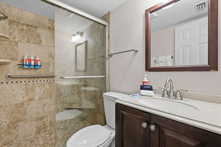 Refresh after a day at the beach in this updated bathroom featuring a spacious walk-in tile shower and modern finishes. A comfortable beach stay with all the essentials for relaxation.