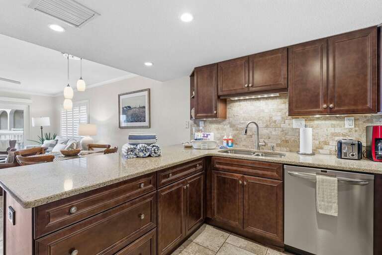 This stylish beach condo kitchen features granite countertops, stainless steel appliances, and an