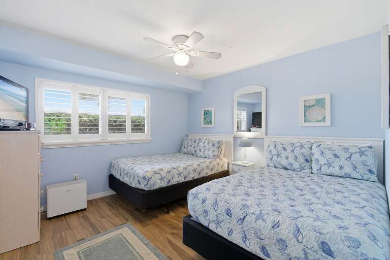 Comfortable beach stay bedroom with two beds, coastal décor, and plenty of natural light. Perfect for families or friends, unwind in a bright, relaxing space after a fun-filled day by the ocean.