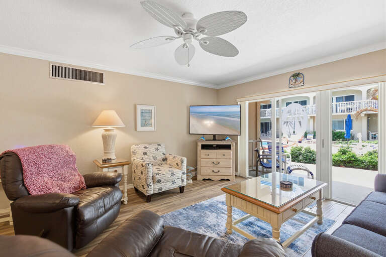 Relax in this inviting beach stay living room with comfy seating, TV, and sliding doors to the