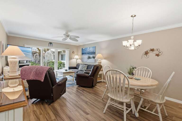 Spacious open living and dining area with coastal décor, comfy seating, and patio access. This