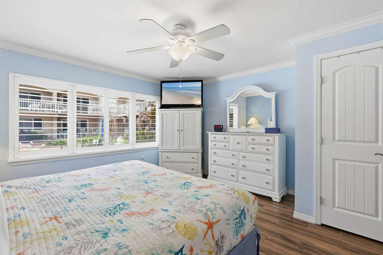 Spacious beach stay bedroom with soft coastal tones, comfy bed, and TV. Enjoy natural light and a relaxing atmosphere—perfect for unwinding after a day spent by the ocean.