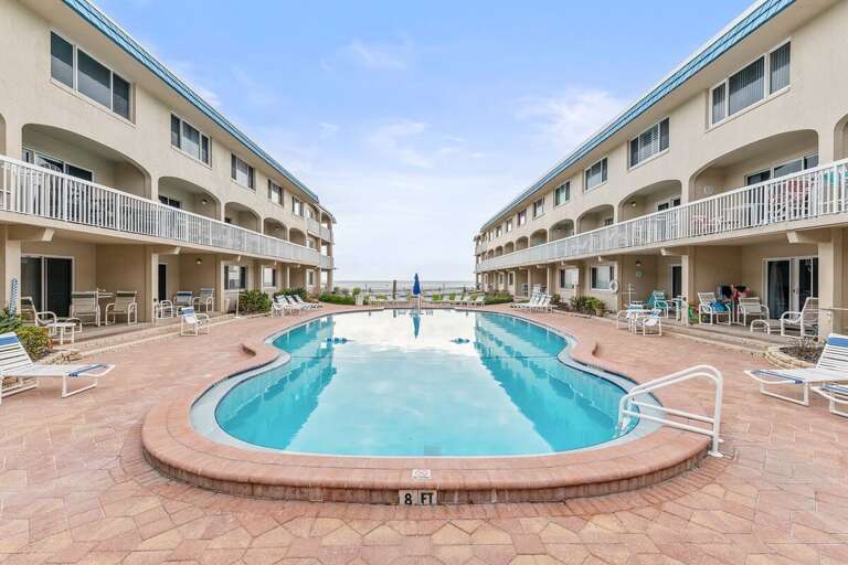 Stunning pool area with ocean views, lounge chairs, and spacious sun deck. Enjoy the ultimate beach stay with relaxing poolside moments just steps from the sand and surf.
