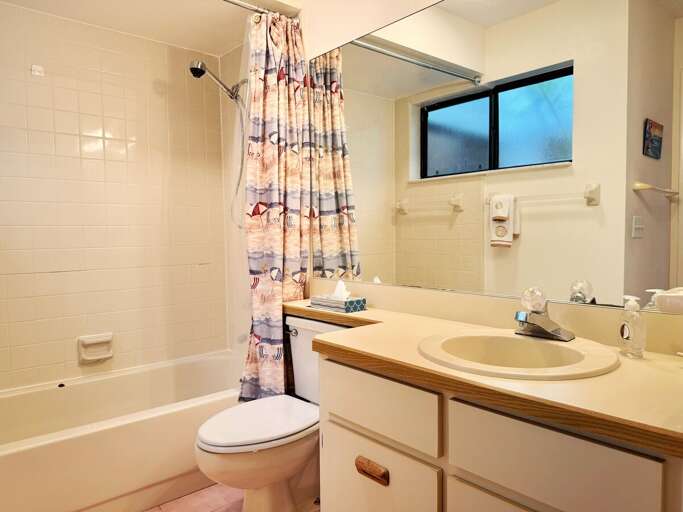 Freshen up after a day at the beach in this full bathroom featuring a tub/shower combo, large vanity with ample counter space, and seaside-inspired décor for a relaxing coastal touch.