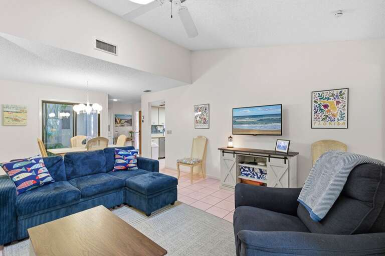 This inviting open living and dining area features plush seating, coastal décor, and a smart