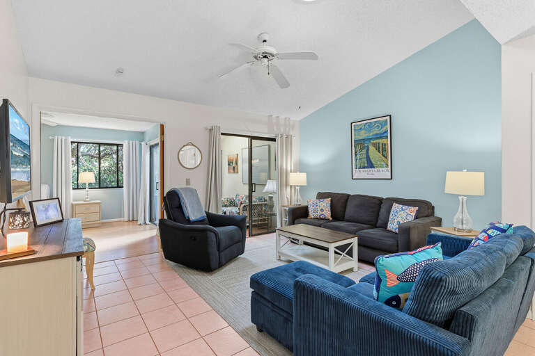 Relax in this bright, open living area with vaulted ceilings, cozy seating, and coastal décor. With