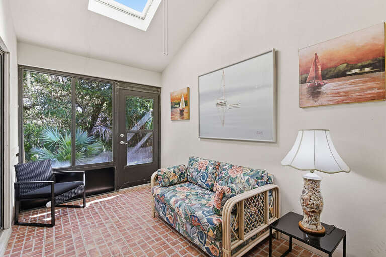 Unwind in this charming sunroom with tropical views, cozy seating, and coastal artwork. A peaceful