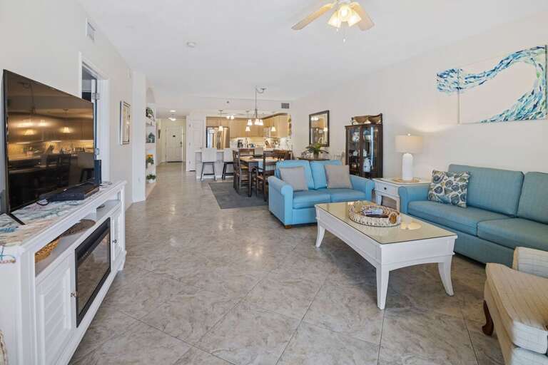 Bright, open living area with coastal décor, comfy seating, and direct flow to the kitchen—perfect for relaxing after a day at the beach or entertaining with friends and family.