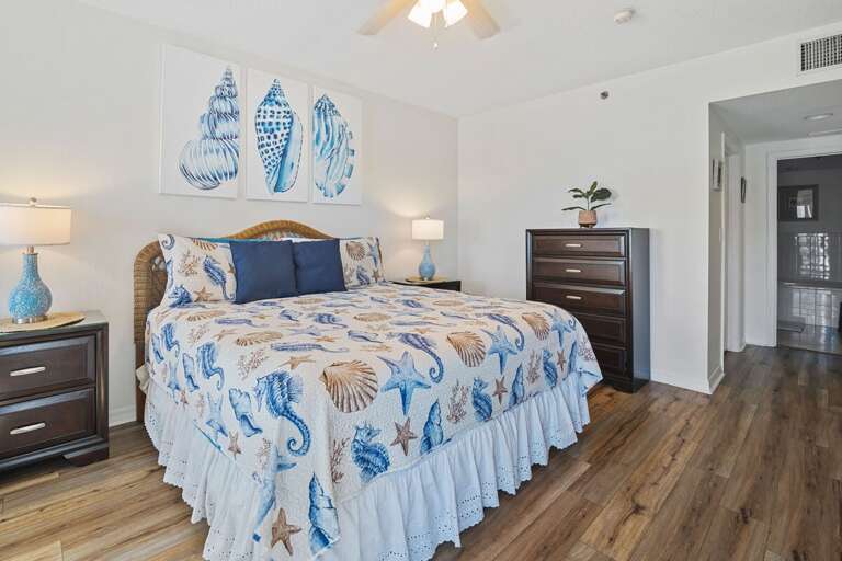 Drift into relaxation in this beach-themed bedroom, featuring a plush king bed with seashell and seahorse bedding, soft lighting, and a calming coastal ambiance perfect for your seaside getaway.