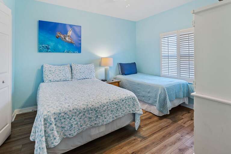 Perfect for families, this bright beach-style room features a full and twin bed, coastal décor, and calming ocean tones—ideal for a relaxing beach getaway.